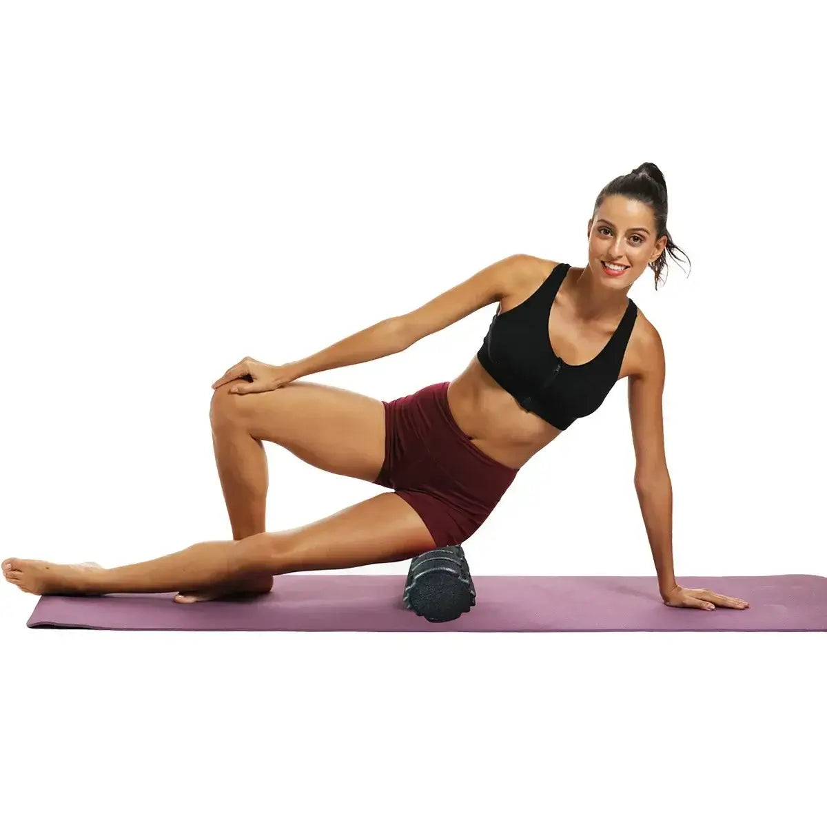 Woman using high-density foam roller 33cm on a yoga mat for fitness exercises in a home workout.