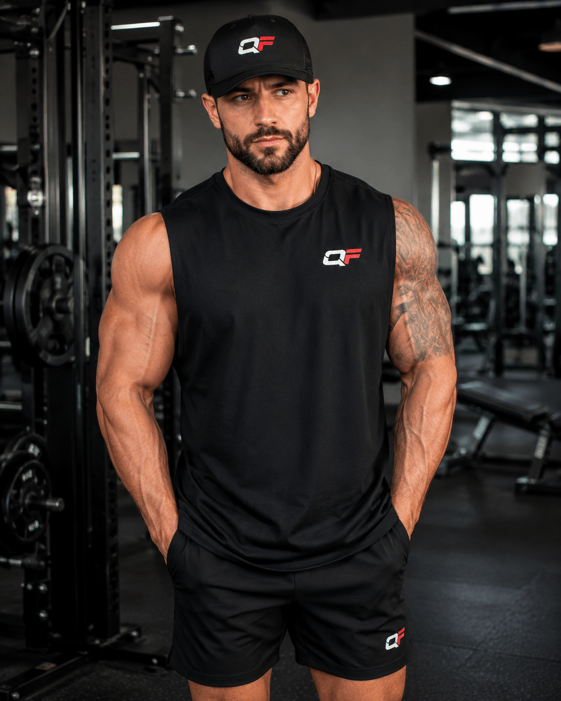 Man wearing a black mesh trucker cap and sleeveless shirt in a gym setting, showcasing fitness style.