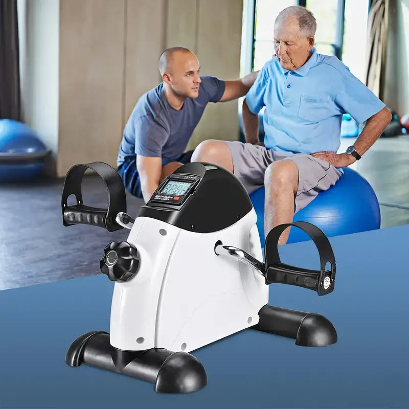 Mini pedal exercise machine for home fitness used during a workout session with a trainer and a senior individual.