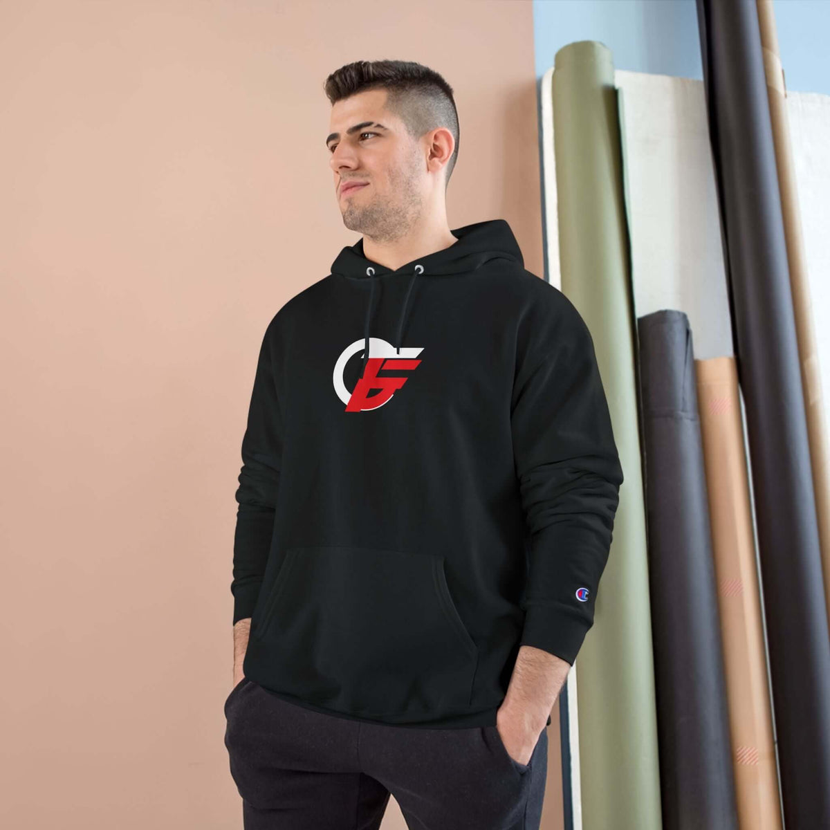 Man wearing an athletic black champion hoodie with a red and white emblem, perfect for casual wear and training.