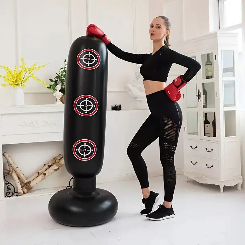 Woman in boxing gear using an inflatable boxing bag for home workouts in a bright room.