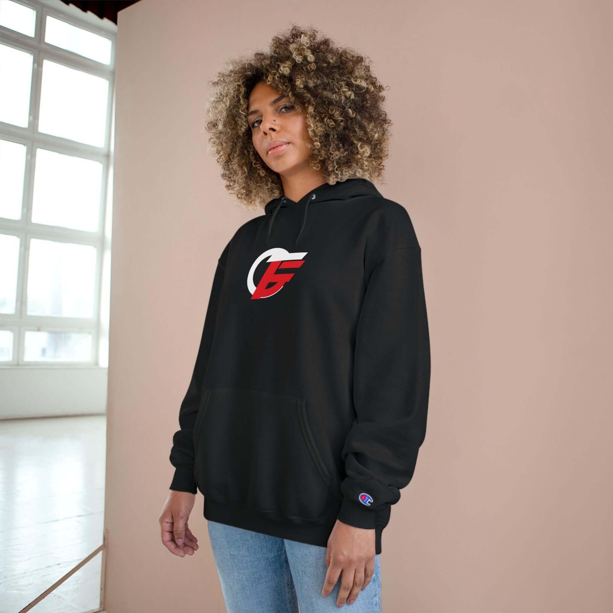 athletic black champion hoodie worn by a model, featuring a prominent red and white emblem on a pullover design.