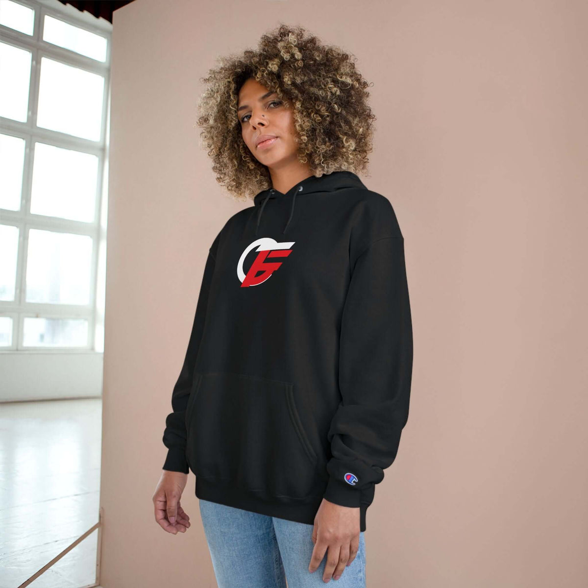 athletic black champion hoodie worn by a model, featuring a prominent red and white emblem on a pullover design.