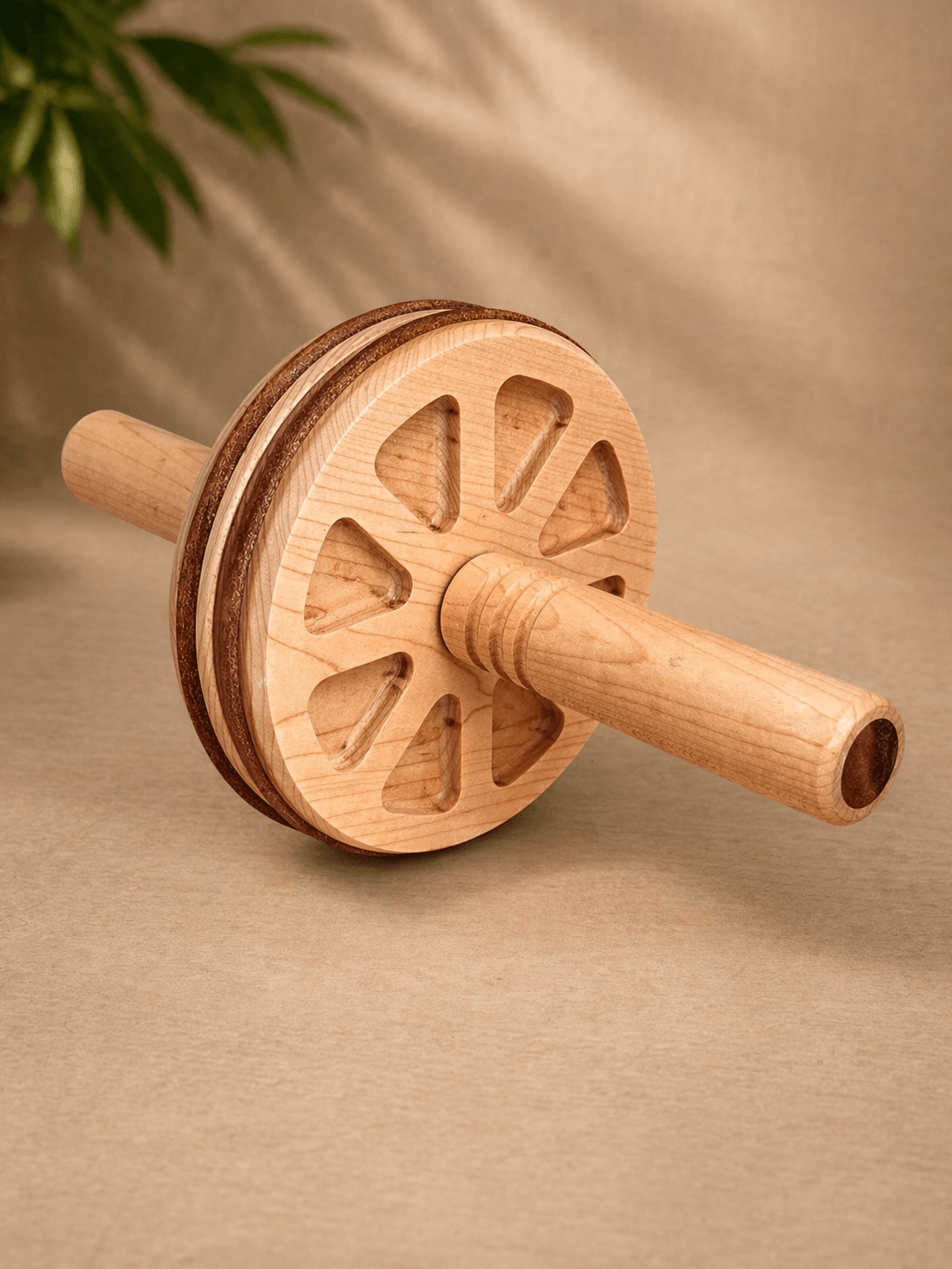 Handcrafted wooden ab wheel home fitness on a beige background with green plant accents.