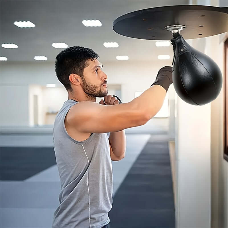 Man training with hanging pear-shaped boxing speed ball in a gym setting.