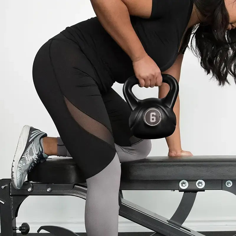 Woman using a 6kg kettlebell for strength training during a workout routine on a bench.