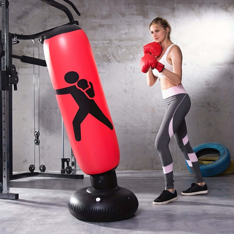 Woman training with a durable inflatable boxing bag stand in a gym setting, enhancing her fitness routine.