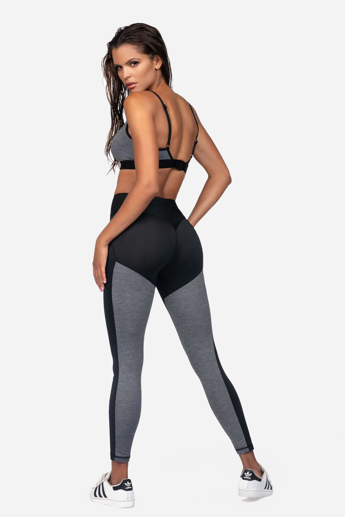 Model wearing a comfortable sports bra for fitness with matching leggings from the back in a studio setting.