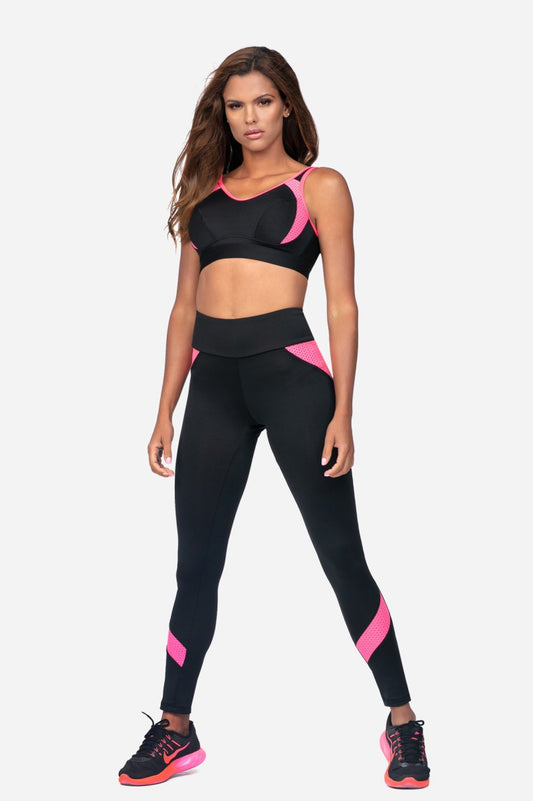Women's black pink sports bra for training model wearing matching leggings and athletic shoes.