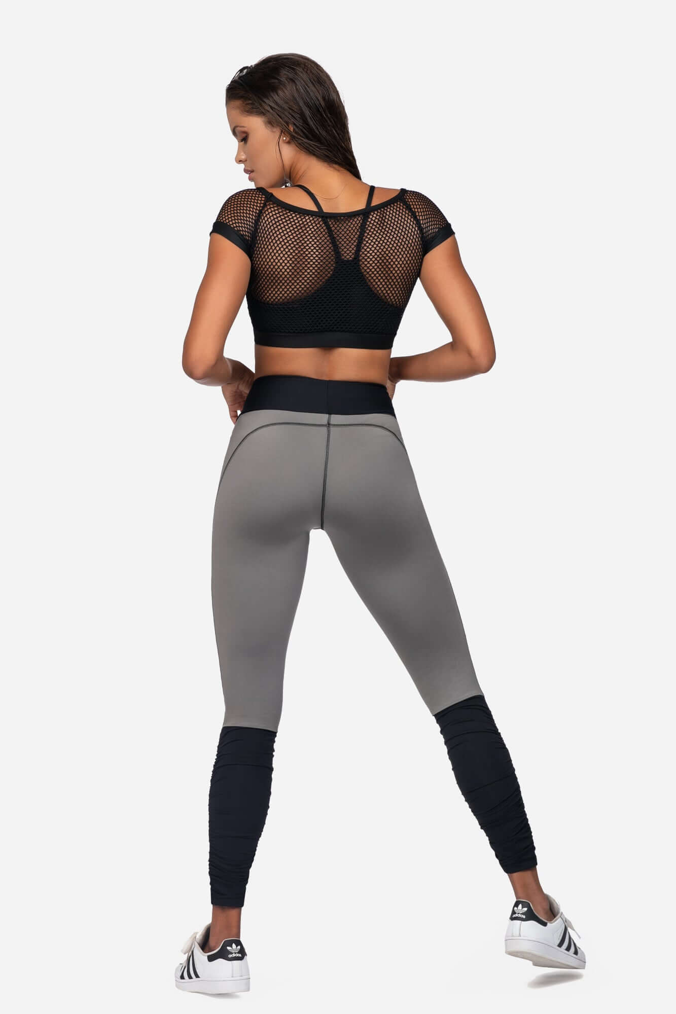 Model showcasing XL fitness leggings for active wear, styled with a black mesh crop top and stylish sneakers.