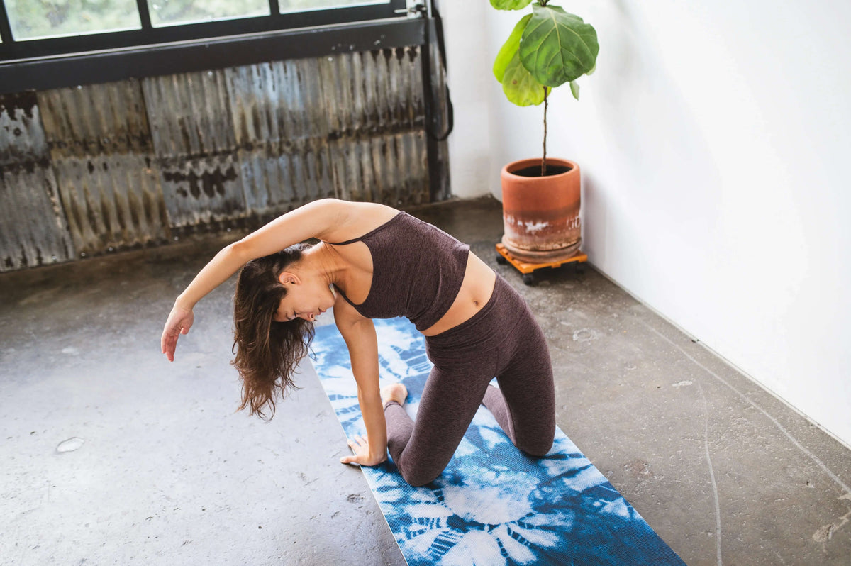 Woman practicing yoga on an Ataraxy non-slip yoga mat with cushioned support in a serene indoor space.