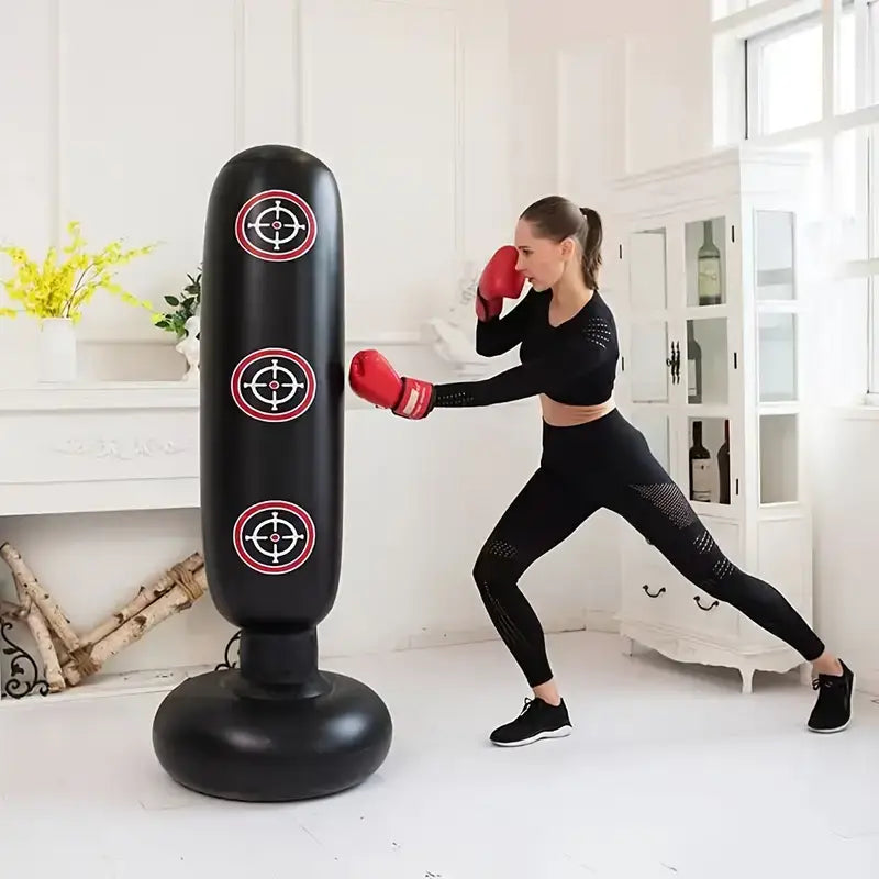 Woman using an inflatable boxing bag for home workouts with red gloves in a bright room.