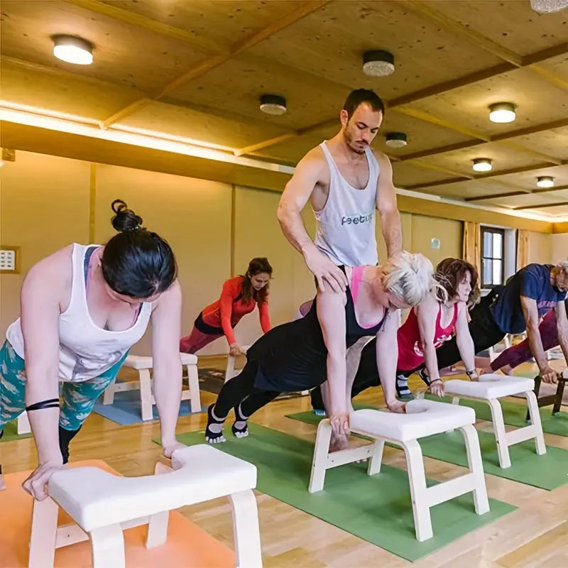 Group yoga class using padded yoga chair stands for headstands and workouts, demonstrating various exercises for fitness.