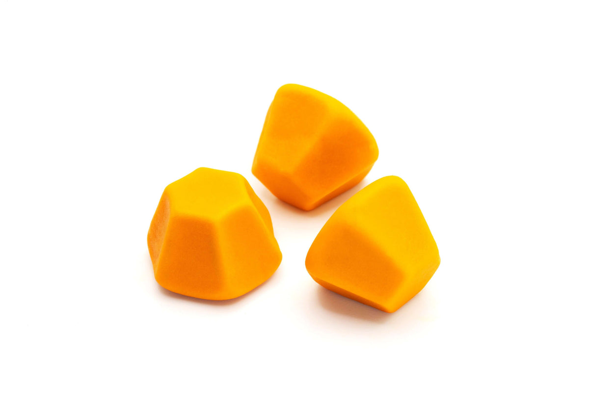 Curcumin ginger dietary supplement in the form of orange gummy-like shapes on a white background.