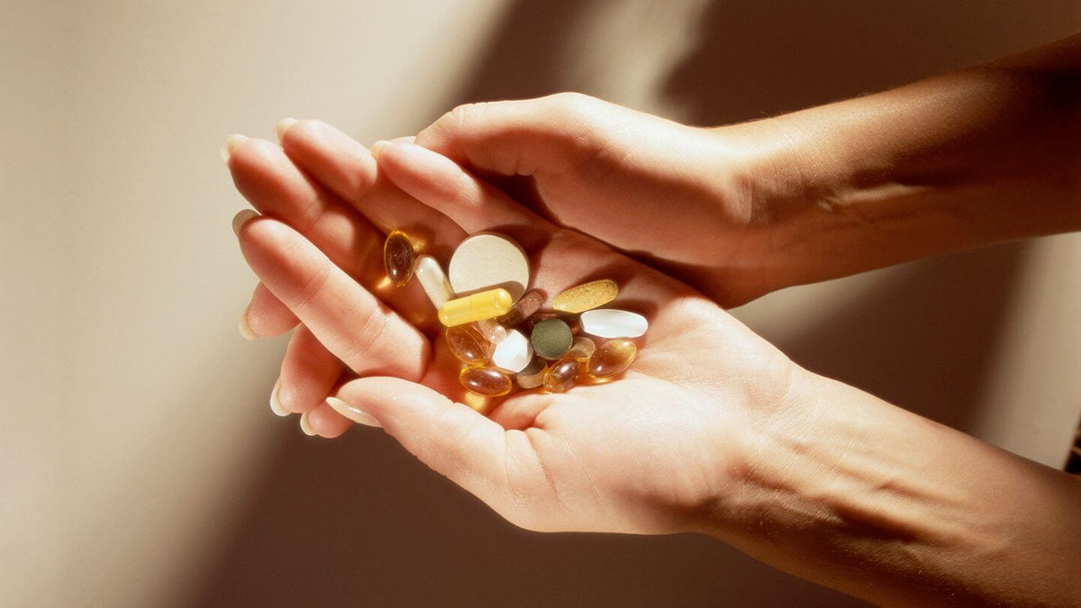 hands holding various multivitamins for an active lifestyle, supporting women's health with a daily routine.