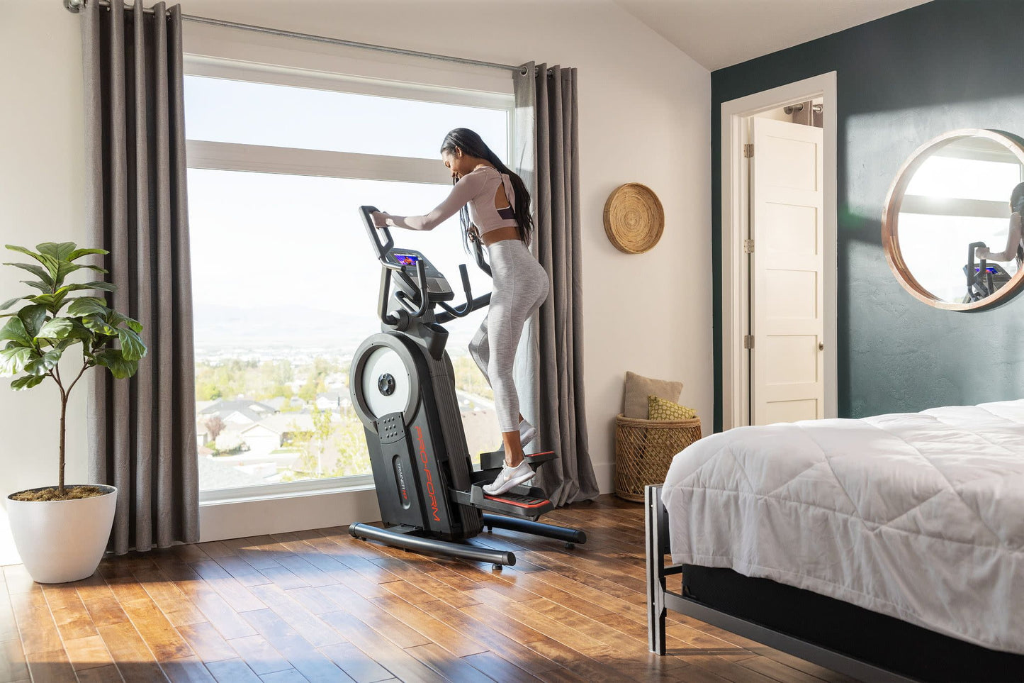Fitness Essentials Trainer H7 iFit-enabled elliptical with 7-inch touchscreen and built-in fan, shown in a workout setting.