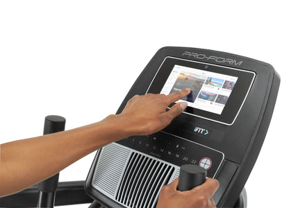 Fitness Essentials Trainer H7 iFit-enabled elliptical with 7-inch touchscreen and built-in fan, displayed in a modern gym setting.
